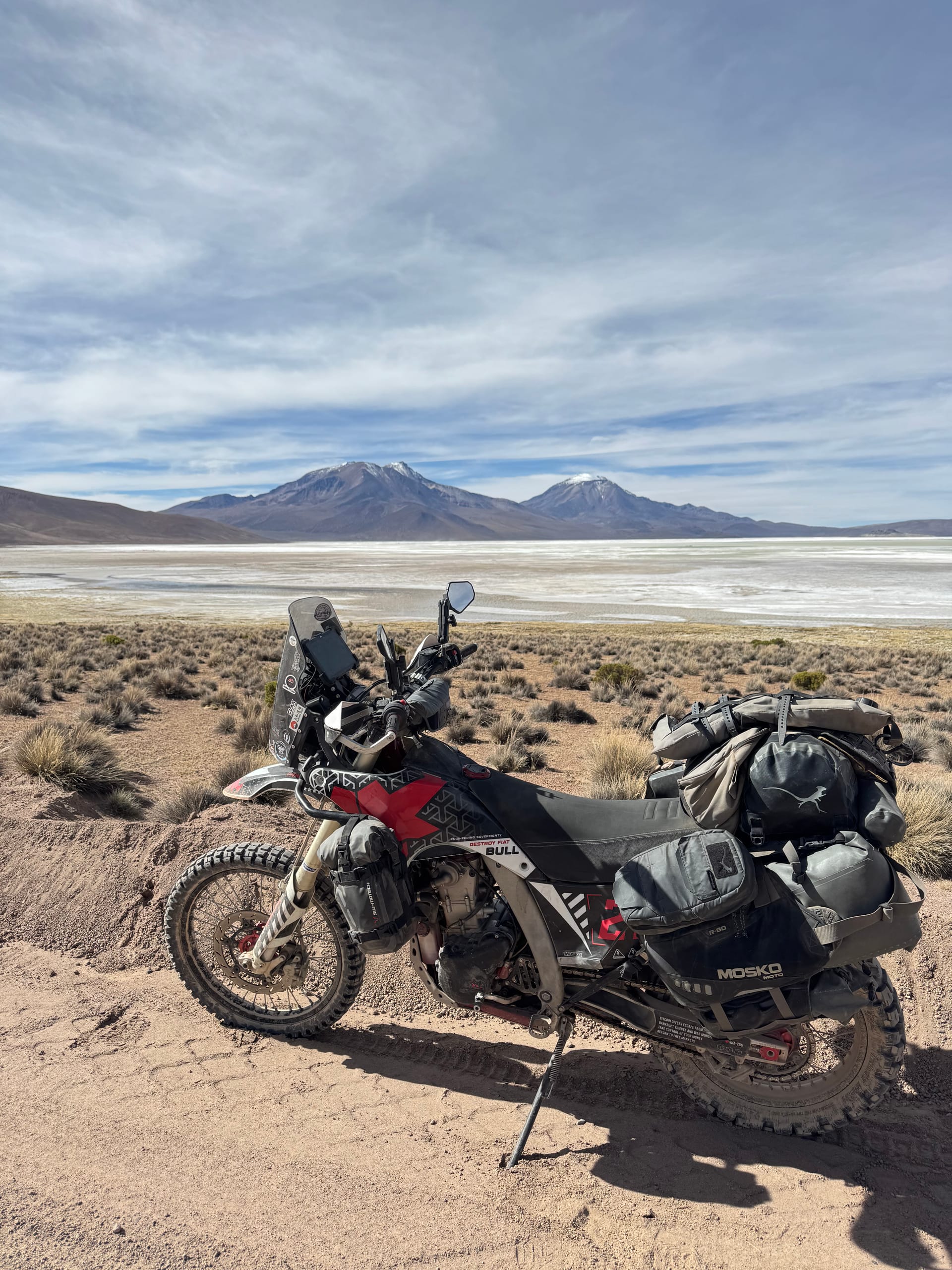 Moto de Thomas chargée devant le salar et les volcans, nord du Chili